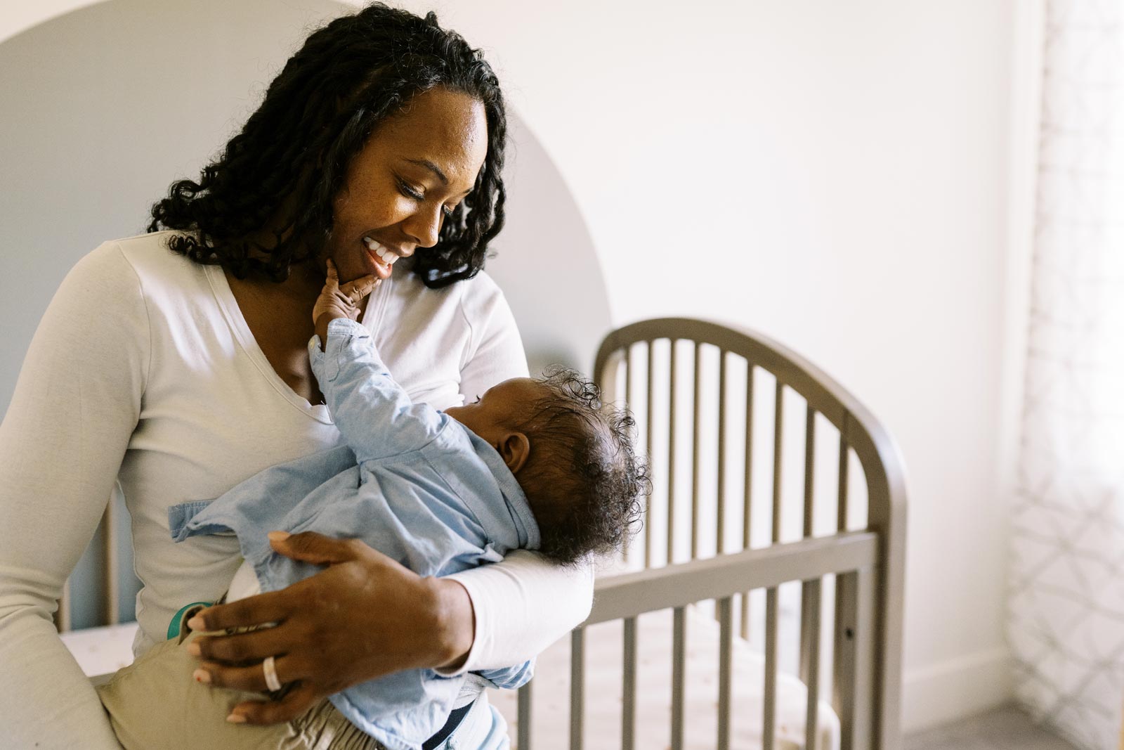Mother cradling her newborn baby, with crib in background