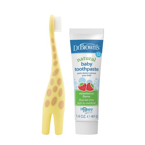 A baby toothbrush with a yellow giraffe design is next to a tube of Dr. Brown's natural baby toothpaste. The toothpaste tube features strawberry graphics and text indicating it's fluoride-free and safe to swallow.