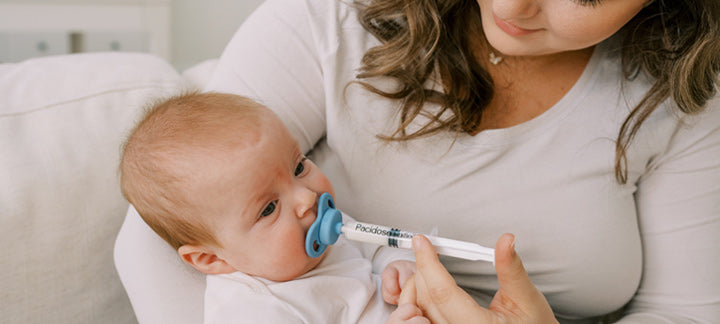 Mother giving infant medicine through Pacidose dispenser