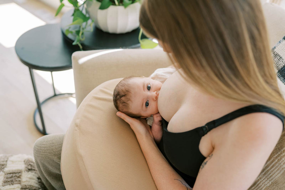 Mother breastfeeding infant while using a support pillow