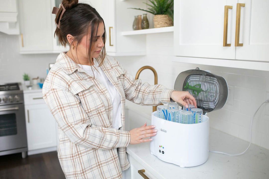 Woman placing bottles inside of sterilizer