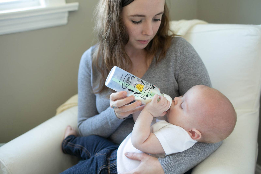 Mother sitting in a chair and bottle feeding her infant