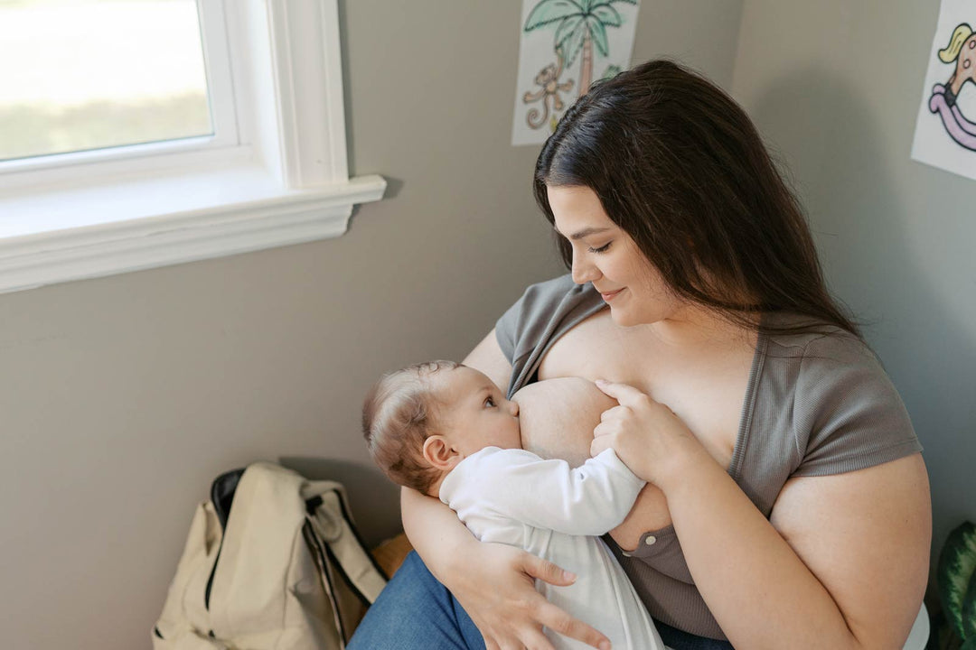 Mother breastfeeding her baby next to a window