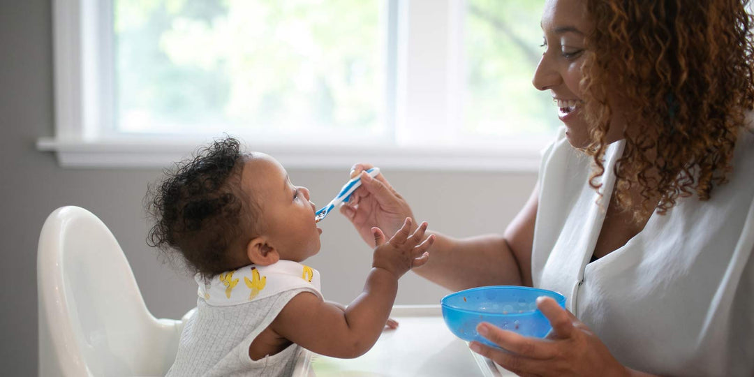 Parent feeding baby with spoon from bowl