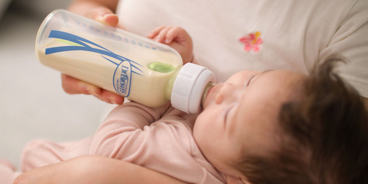 Baby drinking from a glass Dr. Brown's Anti-colic bottle