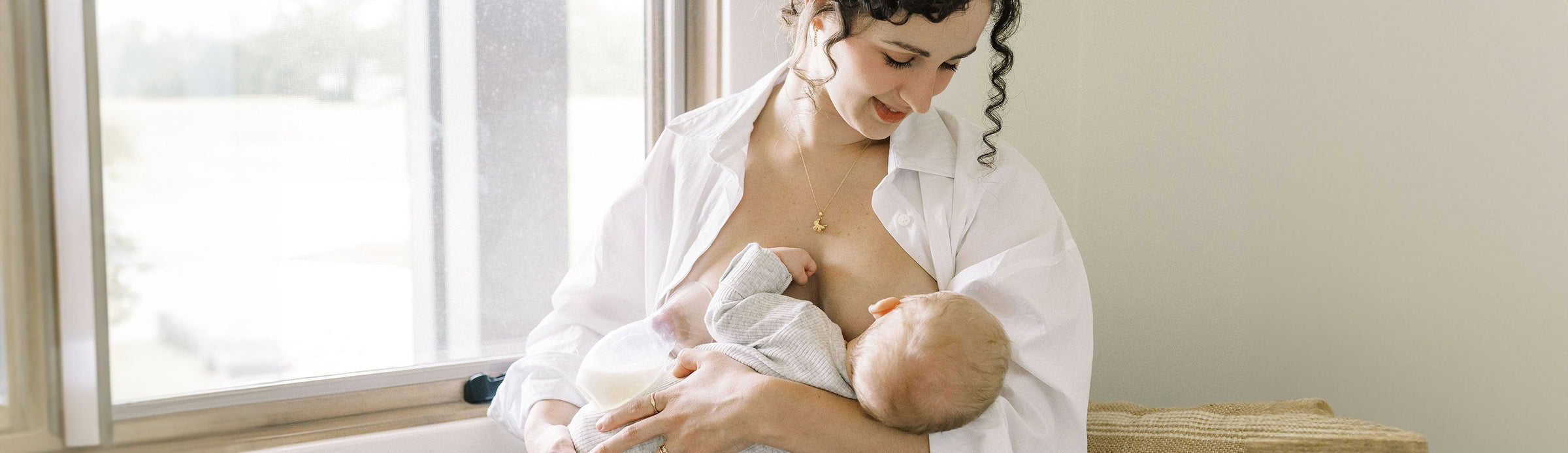 Mom breastfeeding her baby while using the Dr. Brown's Silicone Breast Pump