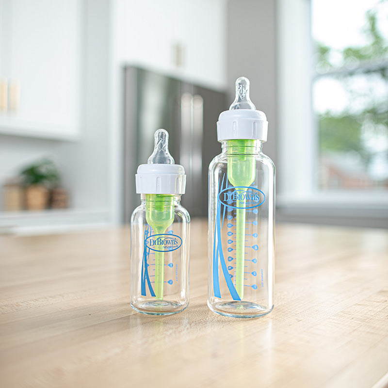 Two Dr. Brown's glass baby bottles on a counter