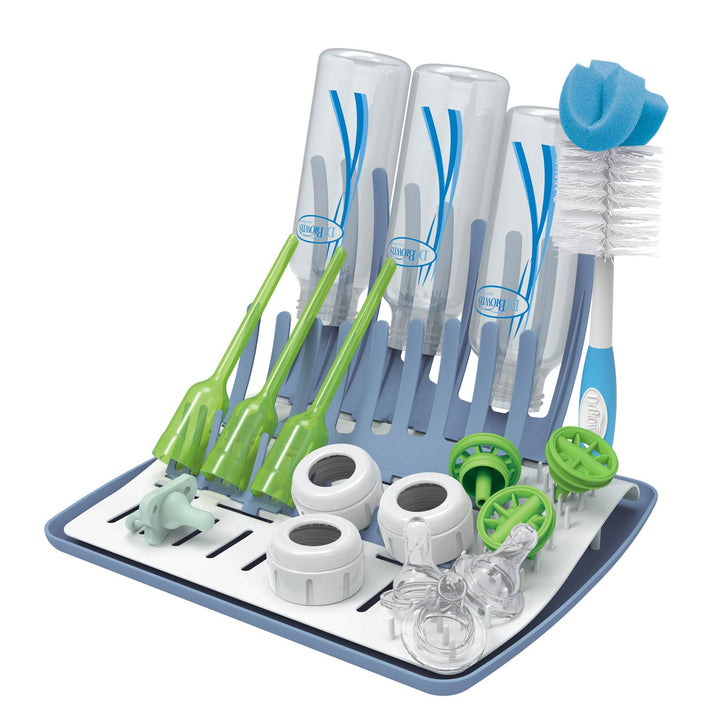 Dr. Brown's™ Folding Baby Bottle Drying Rack features a universal design that holds four inverted bottles, including Dr. Brown's ones, four green brushes, and various baby accessories. It includes a sponge-tipped brush on the side. The blue and white rack has gray sections for organizing.