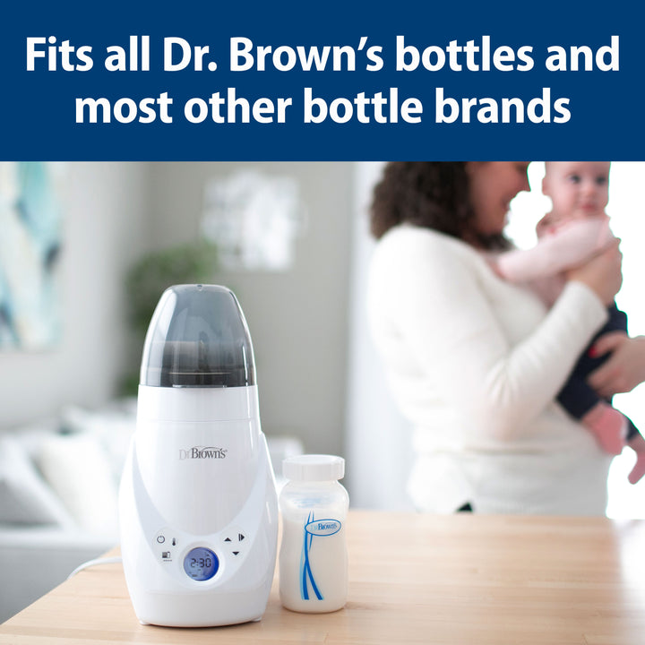 Dr. Brown's bottle warmer on a table with a blurred background of a woman holding a baby.