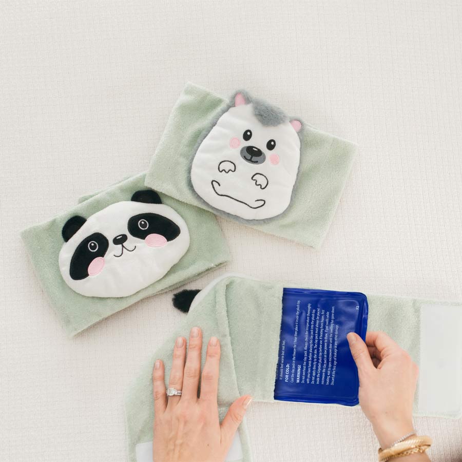 A person places a blue gel pack into a light green fabric pouch featuring a cute hedgehog design. Nearby, there is another pouch with a panda design. Both pouches are on a white textured surface.