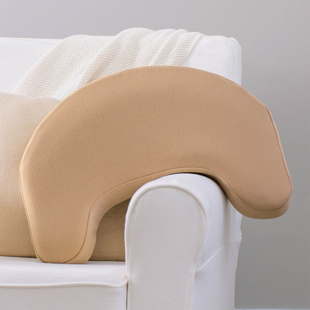 Beige Feeding and Nursing Lap Support Pillow resting against a sofa