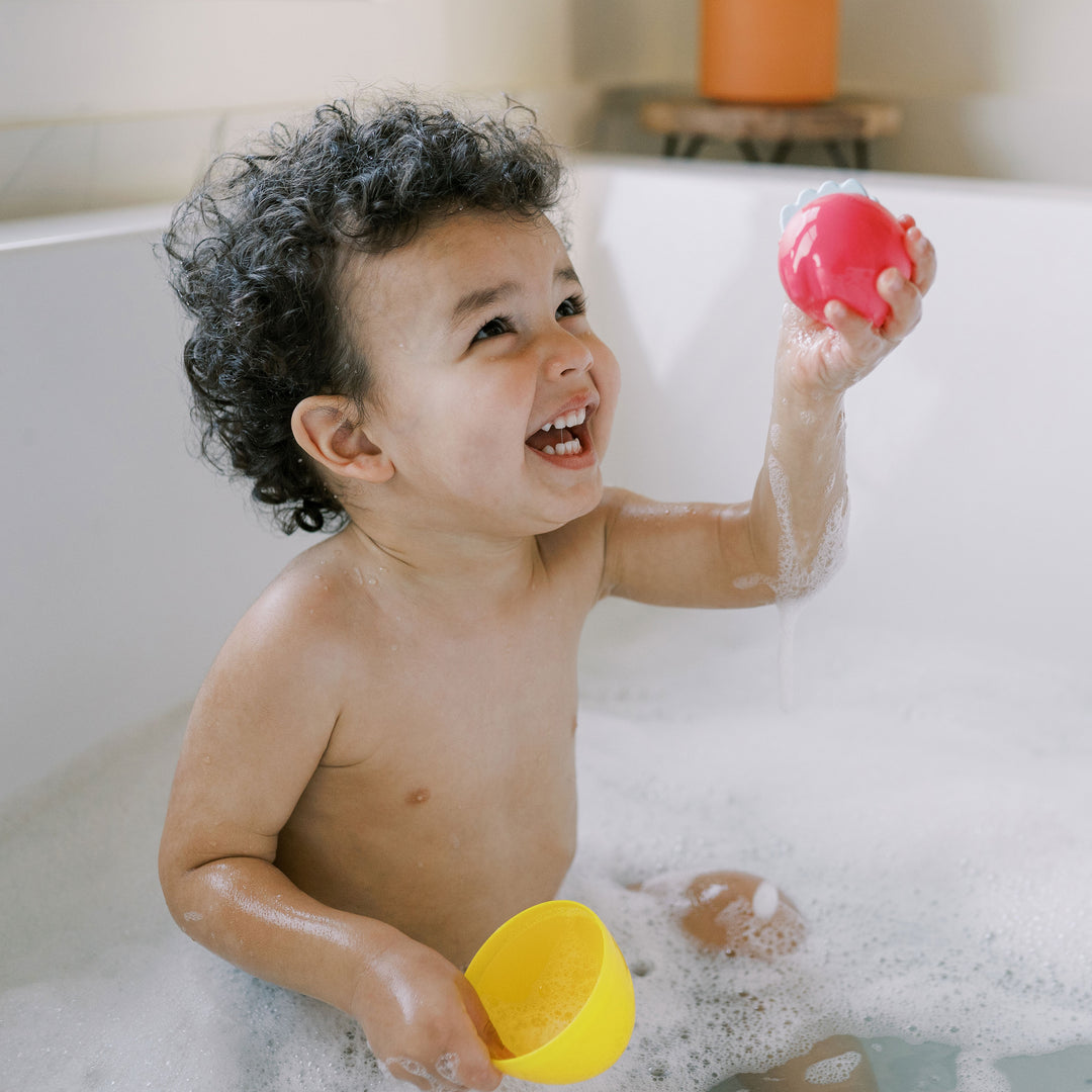 Child playing with Dr. Browns Float and Hatch bath toys in a bathtub