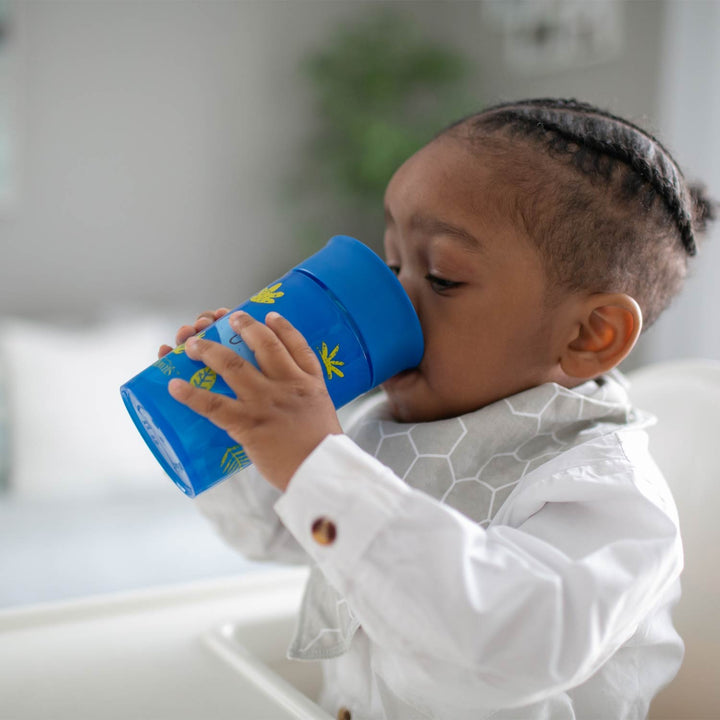 Child drinking from a blue sippy cup indoors