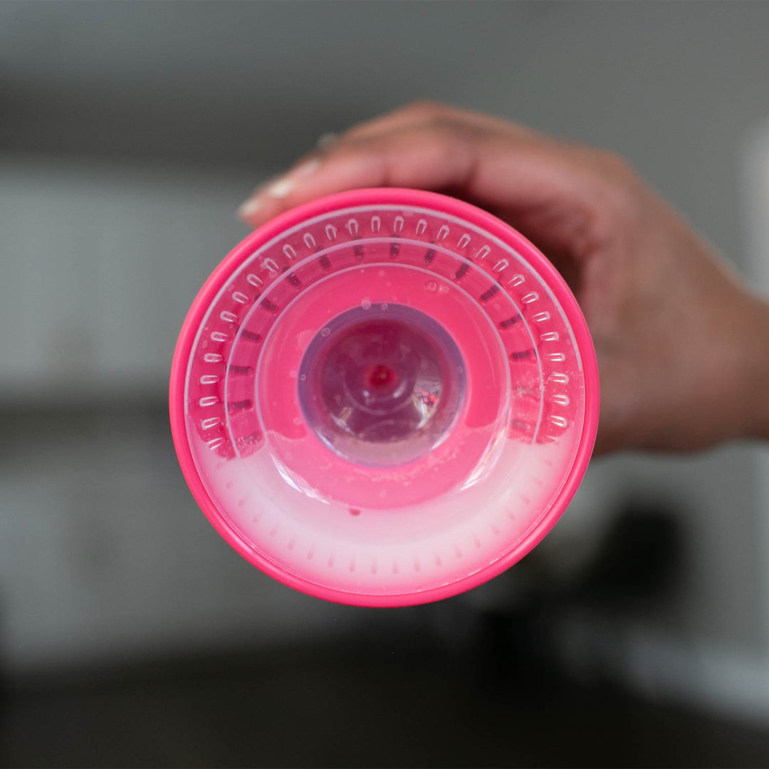 Hand holding a pink and clear plastic container with a textured lid.