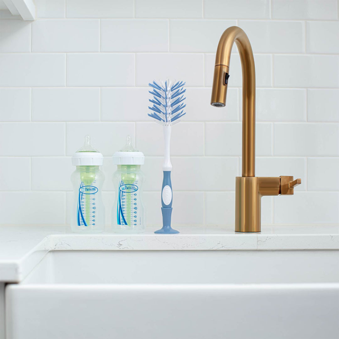 Blue Deluxe Bottle Brush on a sink next to two bottles