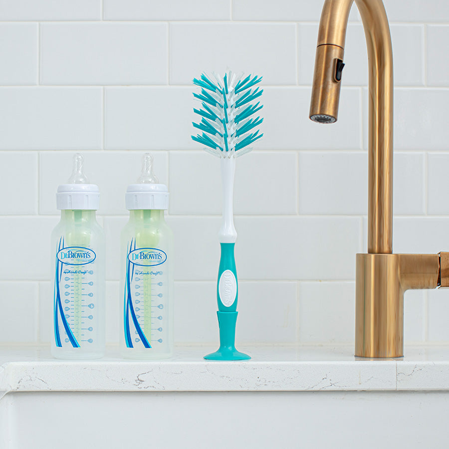 Dr. Brown's Deluxe Bottle Brush on kitchen counter next to the sink with two Dr. Brown's bottles.