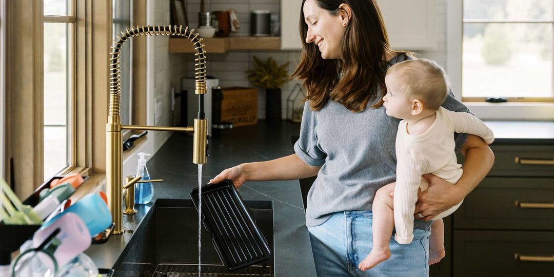 Parent holding infant while at kitchen sink