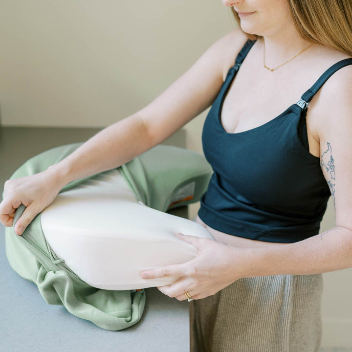 Woman unwrapping green cover for nursing pillow to wash it