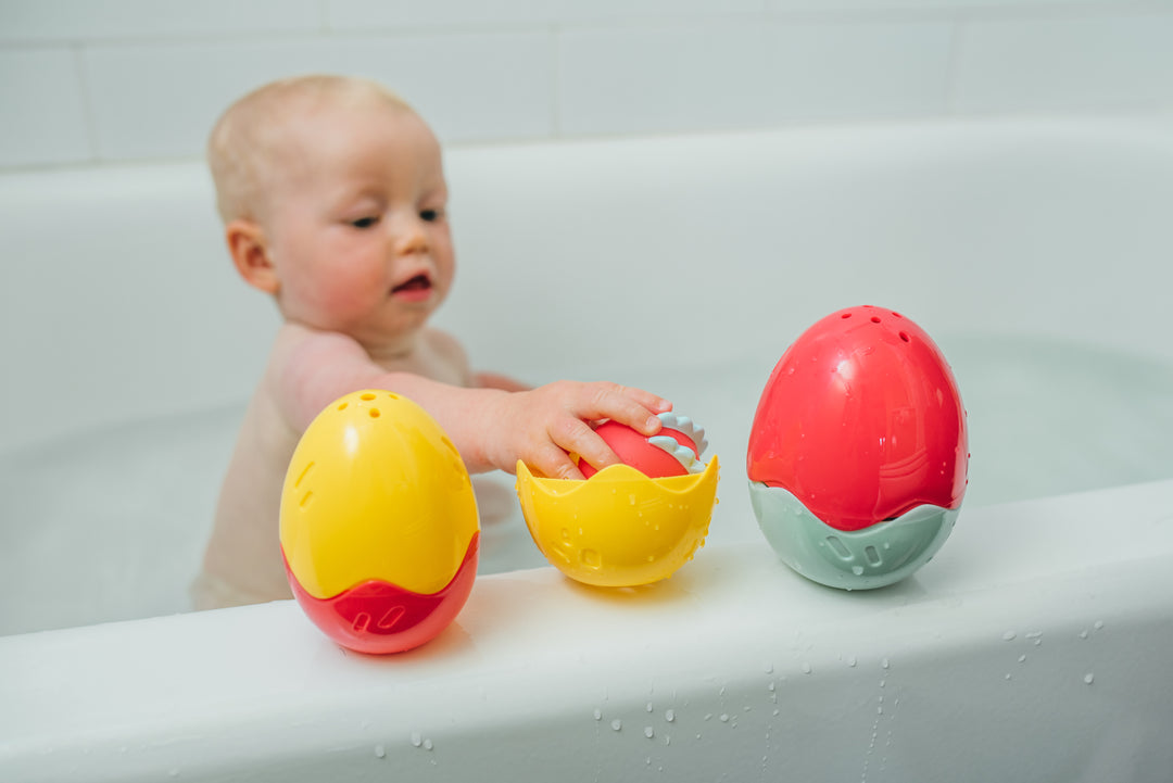 Infant playing with Float and Hatch Dino Egg bath toys
