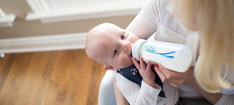 Baby in mother's arms being fed with a bottle