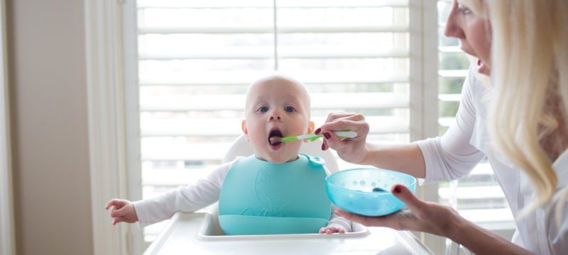 Lifestyle image of mom feeding baby with Scoop-a-bowl and soft tipped spoon