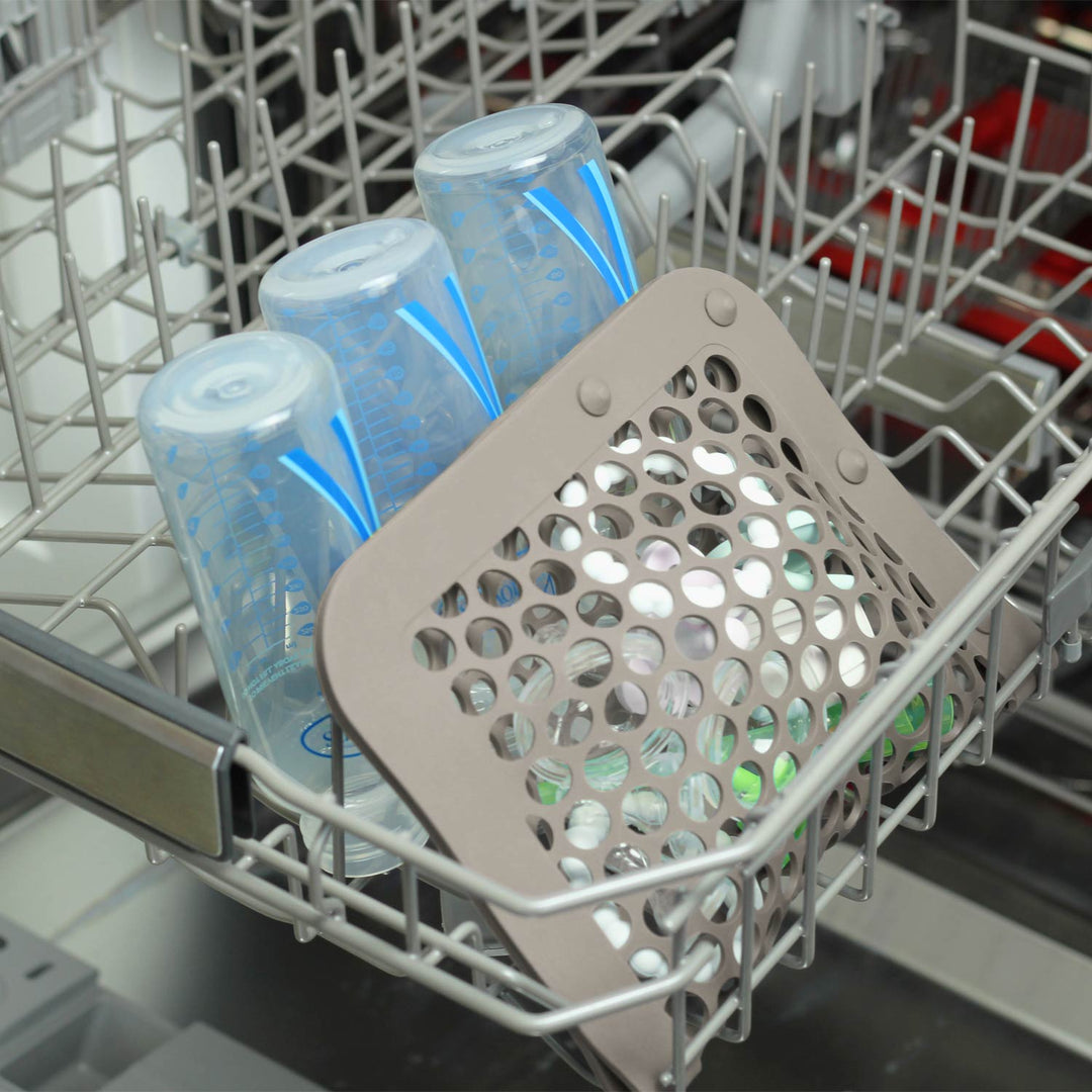 Gray dishwasher bag inside dishwasher next to baby bottles