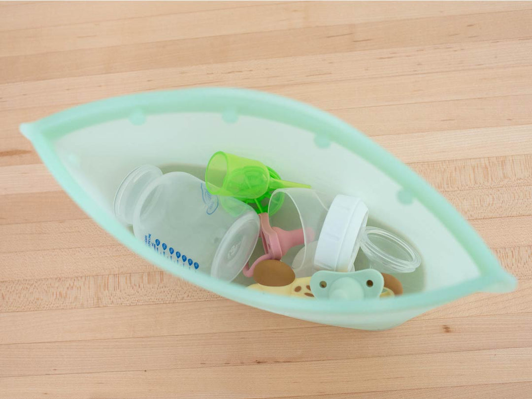 Silicone sterilizer bag with baby bottles and accessories on a wooden surface