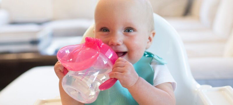 baby drinking from Dr. Brown's Soft Spout Sippy Cup in a highchair