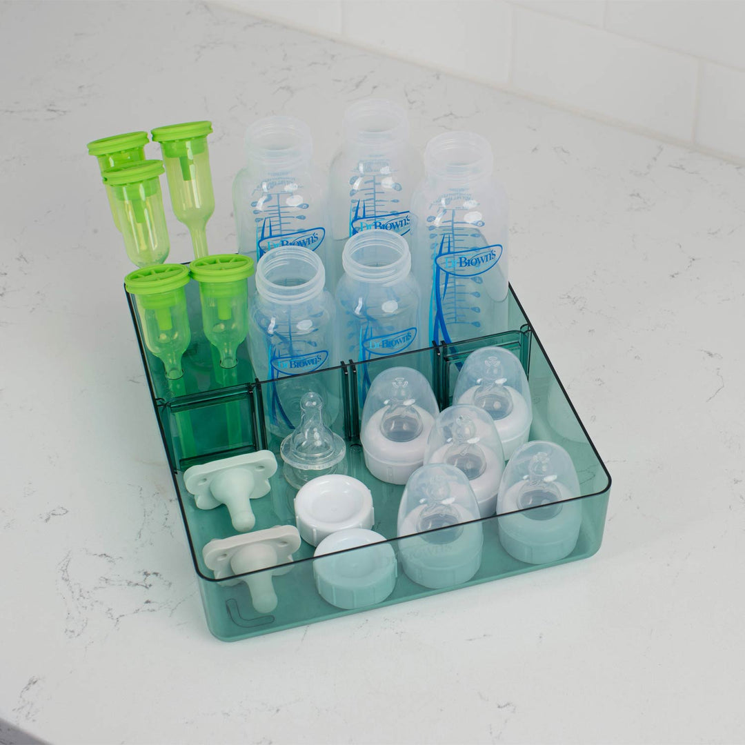 Storage tray with baby bottles, nipples, and pacifiers on a kitchen counter