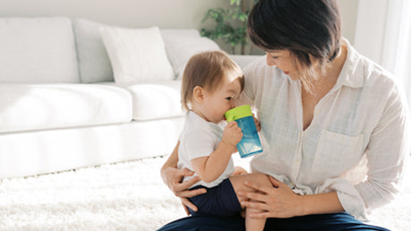 Parent holding a toddler who is drinking from a Straw to 360° Cup