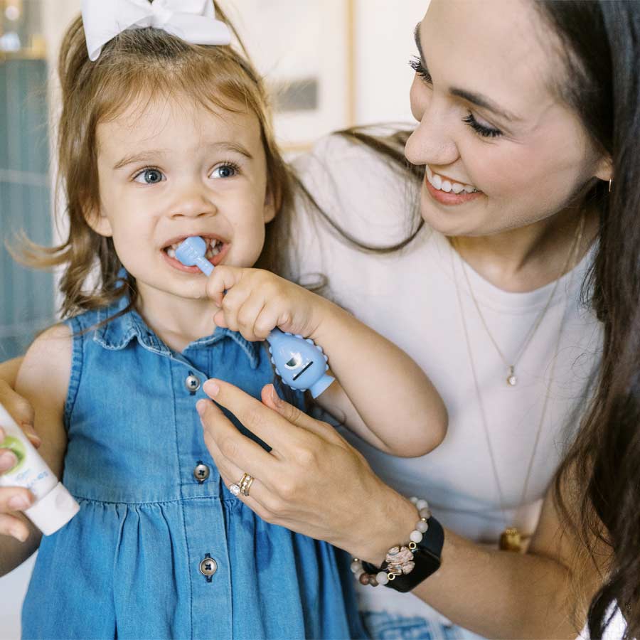 Parent helping toddler brush their teeth