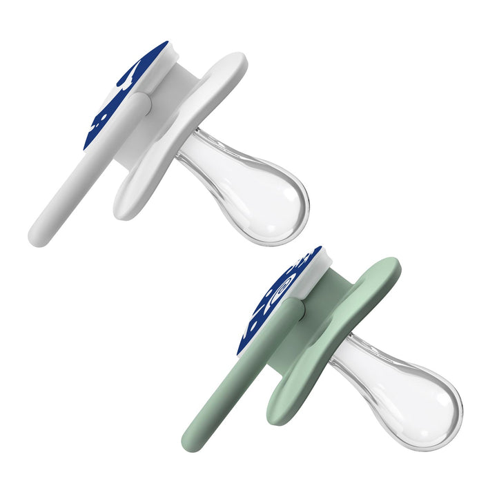 The image shows two Dr. Brown's™ Advantage™ Glow-in-the-Dark Pacifiers, featuring clear, symmetrical teats. One has a white shield with a dark blue handle; the other has a light green shield and matching handle. Both are reversible for easy use and angled for display.