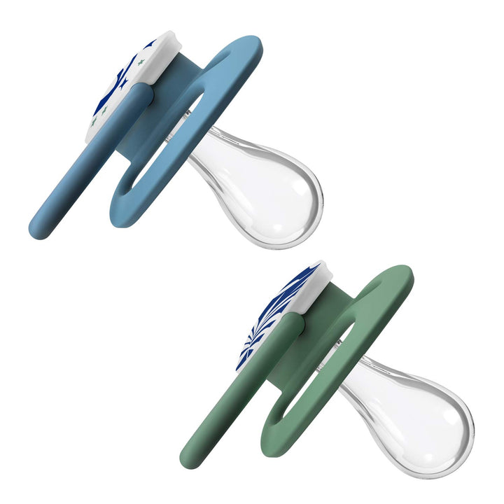 Two Dr. Brown's™ Advantage™ Glow-in-the-Dark Pacifiers are shown: the top one is blue with a white shield and glowing blue star design, while the bottom one is green with a similar pattern. Both feature clear, reversible silicone nipples for versatile comfort.