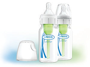 Two baby bottles with green internal components and clear caps, labeled with the brand "Dr. Brown's," are shown. The bottles are positioned on a light, blurred background.