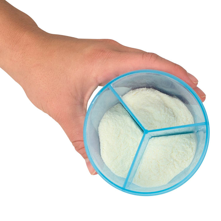 A hand holding a round, three-compartment formula dispenser with a translucent blue rim and powder inside.