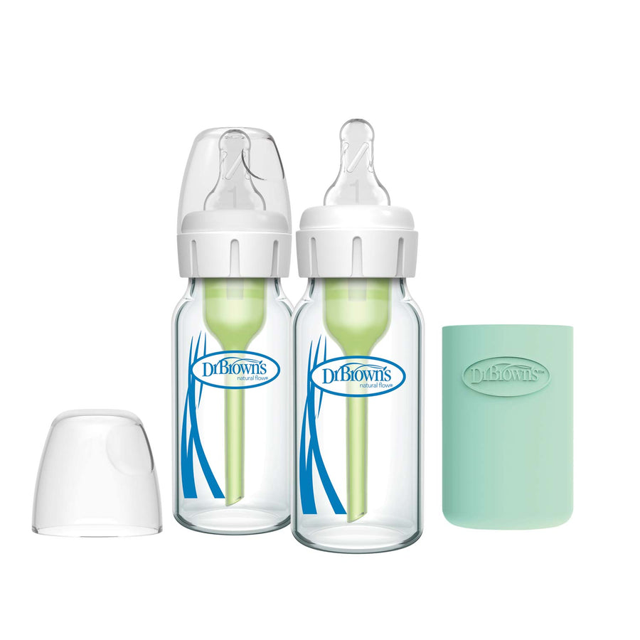 Two Dr. Brown’s Natural Flow® Anti-Colic Options+™ Narrow Glass Baby Bottles with silicone sleeves and clear lids sit side by side, with a separate clear cap and a mint-green sleeve to the right.