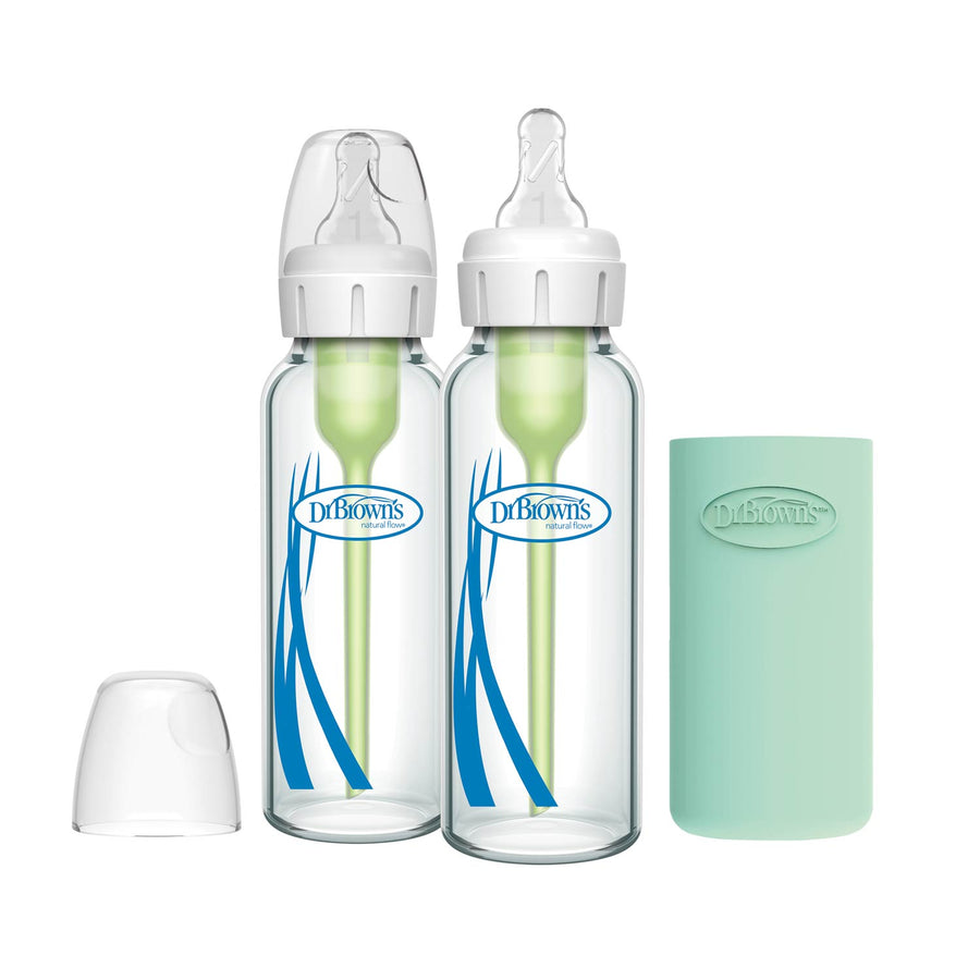 Two Dr. Brown’s Natural Flow® Anti-Colic Options+™ Narrow Glass Baby Bottles with light green silicone sleeves and vent inserts, plus an extra bottle cap, are displayed on a white background.
