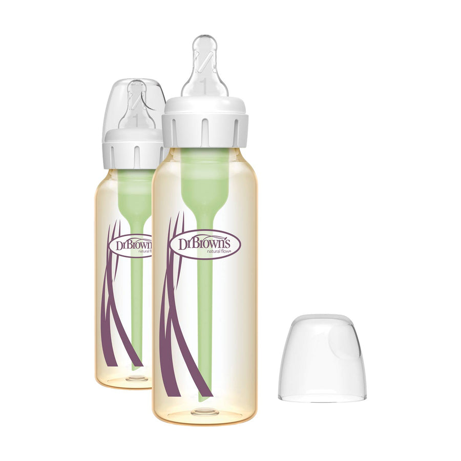Two Dr. Brown's narrow baby bottles with clear plastic bodies, white caps, and green inner liners, with one bottle cap removed and placed to the right.