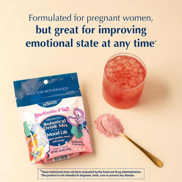 A bag of Dr. Brown's Sweetie Pie Prenatal Botanical Drink Mix is shown next to a glass of pink iced drink, a spoonful of loose pink powder, and promotional text on a warm beige background.