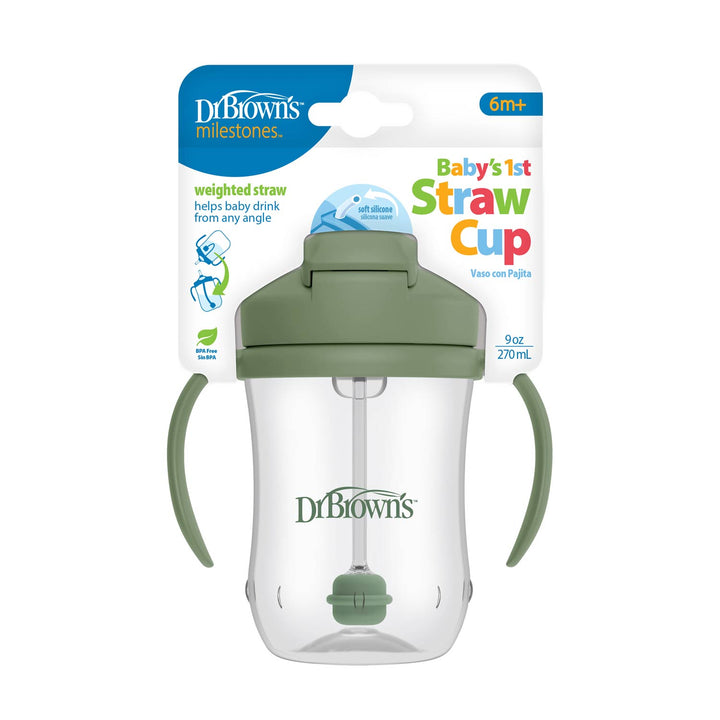 A green Dr. Brown’s™ Milestones™ Baby’s First Straw Cup with handles is shown in its packaging, labeled for ages 6+ months and featuring a weighted, spill-proof straw for easy sipping.