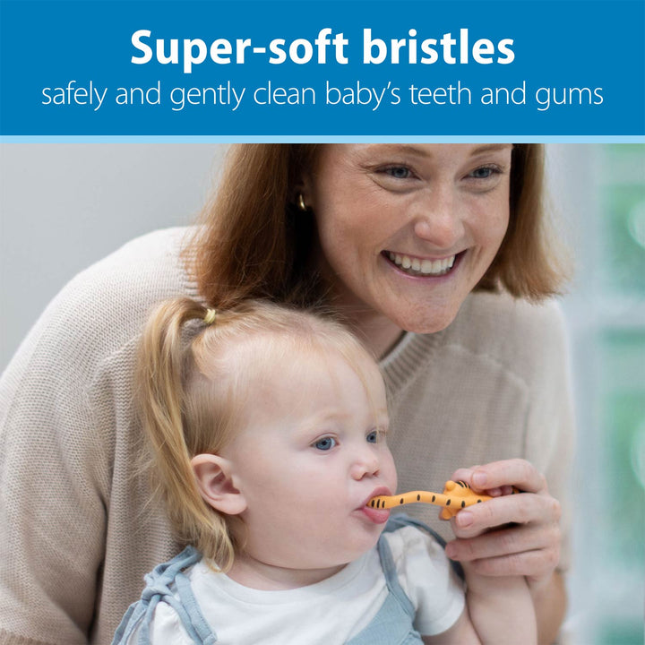 A smiling woman and a young child are shown in a real indoor setting, with the woman holding an orange and black tiger-shaped toothbrush for the child. A blue banner at the top reads, 'Super-soft bristles' and 'safely and gently clean baby's teeth and gums.