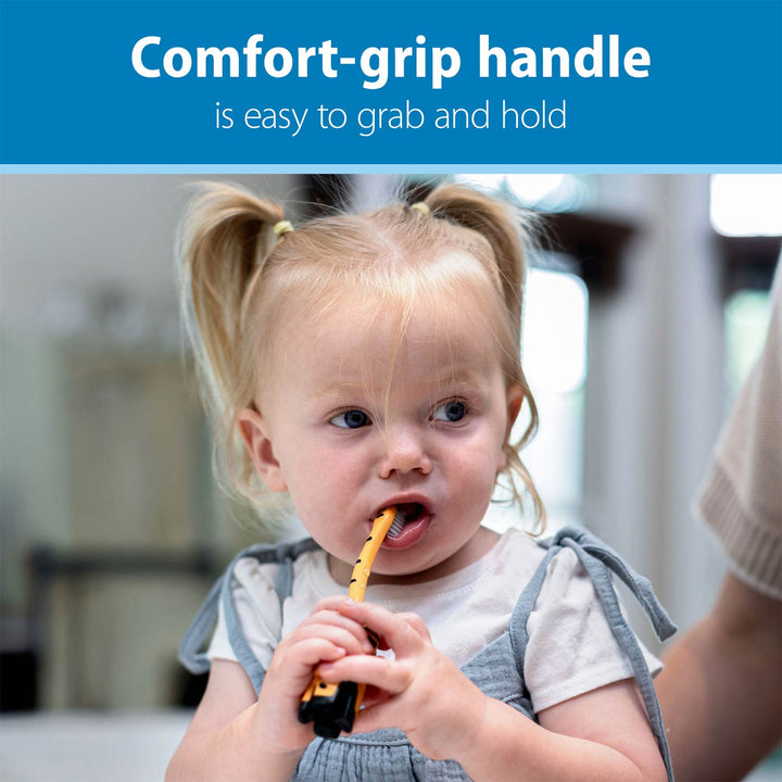 A toddler with blonde pigtails holds a orange and black tiger-shaped toothbrush. A blue banner at the top reads 'Comfort-grip handle is easy to grab and hold'.