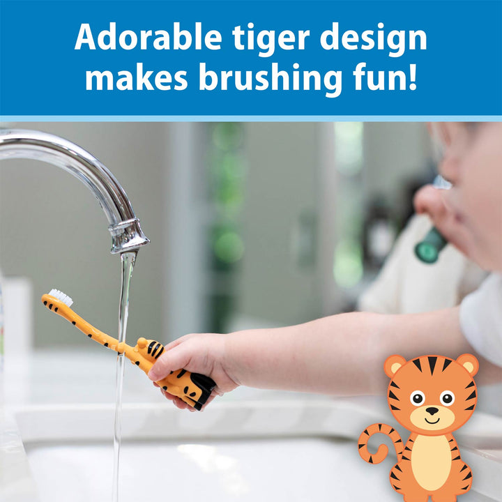 A child's hand holding an orange and black tiger-themed toothbrush under running water at a sink, with a blue banner at the top reading 'Adorable tiger design makes brushing fun!' and a cartoon tiger illustration in the lower right corner.