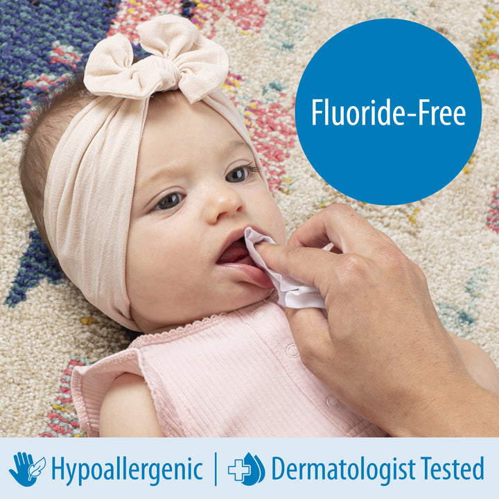 Baby's gums being cleaned with a Dr. Brown's Tooth and Gum Wipe--  fluoride-free with a colorful background