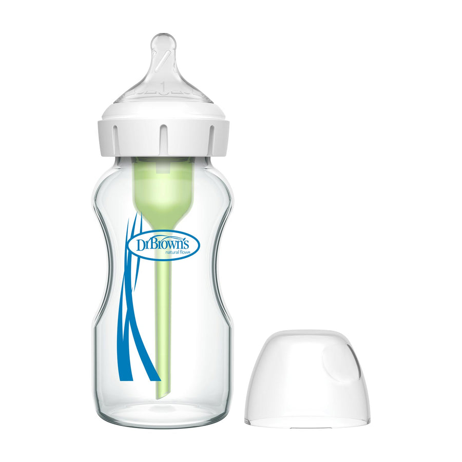 Dr. Brown’s Natural Flow® Anti-Colic Options+™ Wide-Neck Glass Baby Bottle, with Level 1 Slow Flow Nipple, features a white cap, soft nipple, and internal green vent beside a clear cover on a white background.
