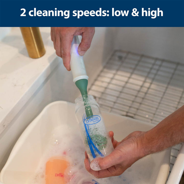 Person using a cleaning brush with two speeds labeled on a kitchen sink.