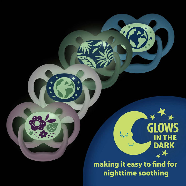 Four pacifiers from Dr. Brown's™ Advantage™ Glow-in-the-Dark collection are arranged diagonally, showcasing distinct designs featuring leaves, flowers, and earth motifs. A smiling crescent moon accompanies the text "GLOWS IN THE DARK," providing easy nighttime soothing. The symmetrical soother design enhances the balance of each set.