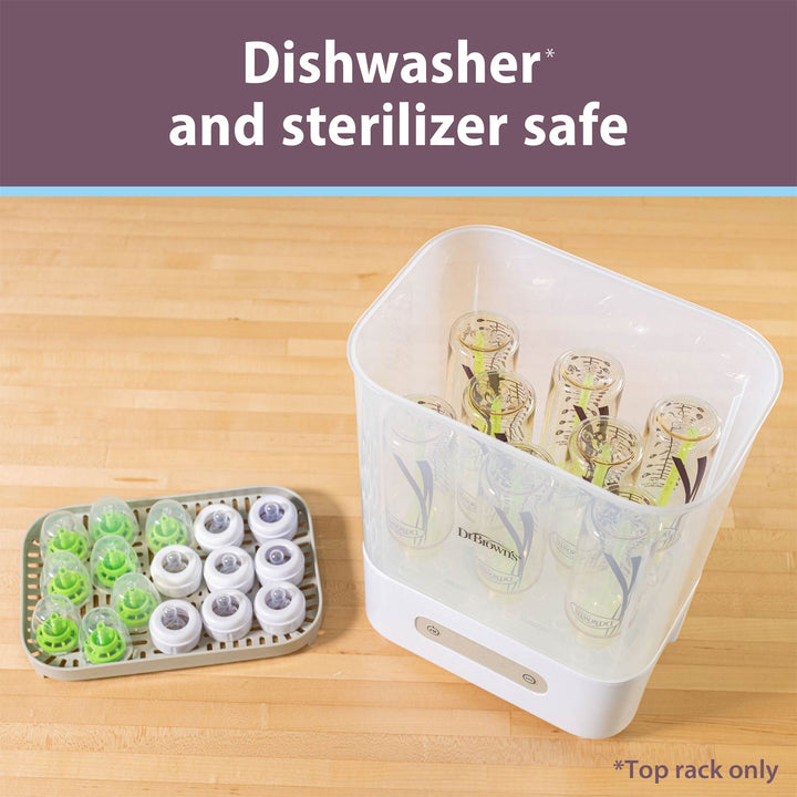 A white and clear dishwasher and sterilizer safe baby bottle warmer shown on a light wood surface, with a tray of detachable green and white dishwasher-safe inserts beside it. Text at the top reads 'Dishwasher and sterilizer safe'.