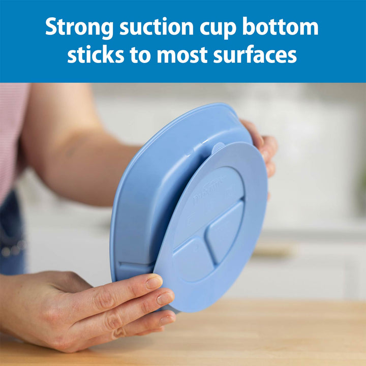 A person holds a light blue No-Slip Divided Suction Plate, with a blue text banner at the top reading 'Strong suction cup bottom sticks to most surfaces.'.