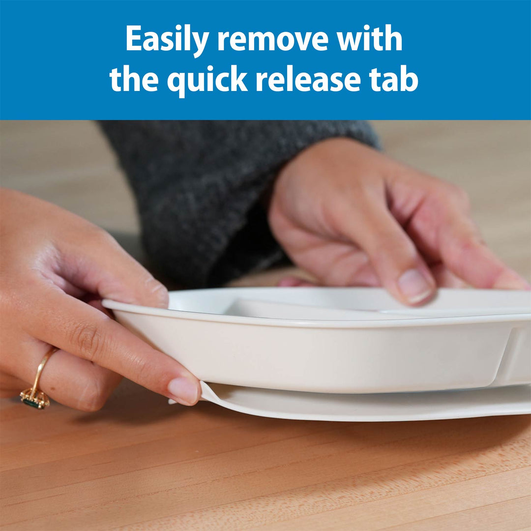 A close-up of a person's hands removing a gray No-Slip Divided Suction Plate from a base, with a blue text banner at the top that reads 'Easily remove with the quick release tab.'.